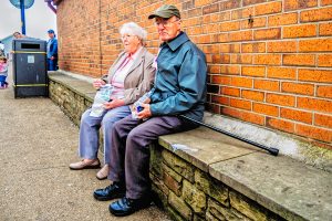 Elderly couple sitting on a bench eating fish and chips