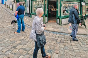 People walking on a cobblestone street. Only the dog notices the photographer